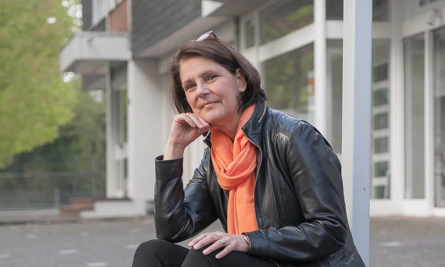 E. Overhage in Lederjacke mit orangem Schal vor dem Betriebsgebäude.